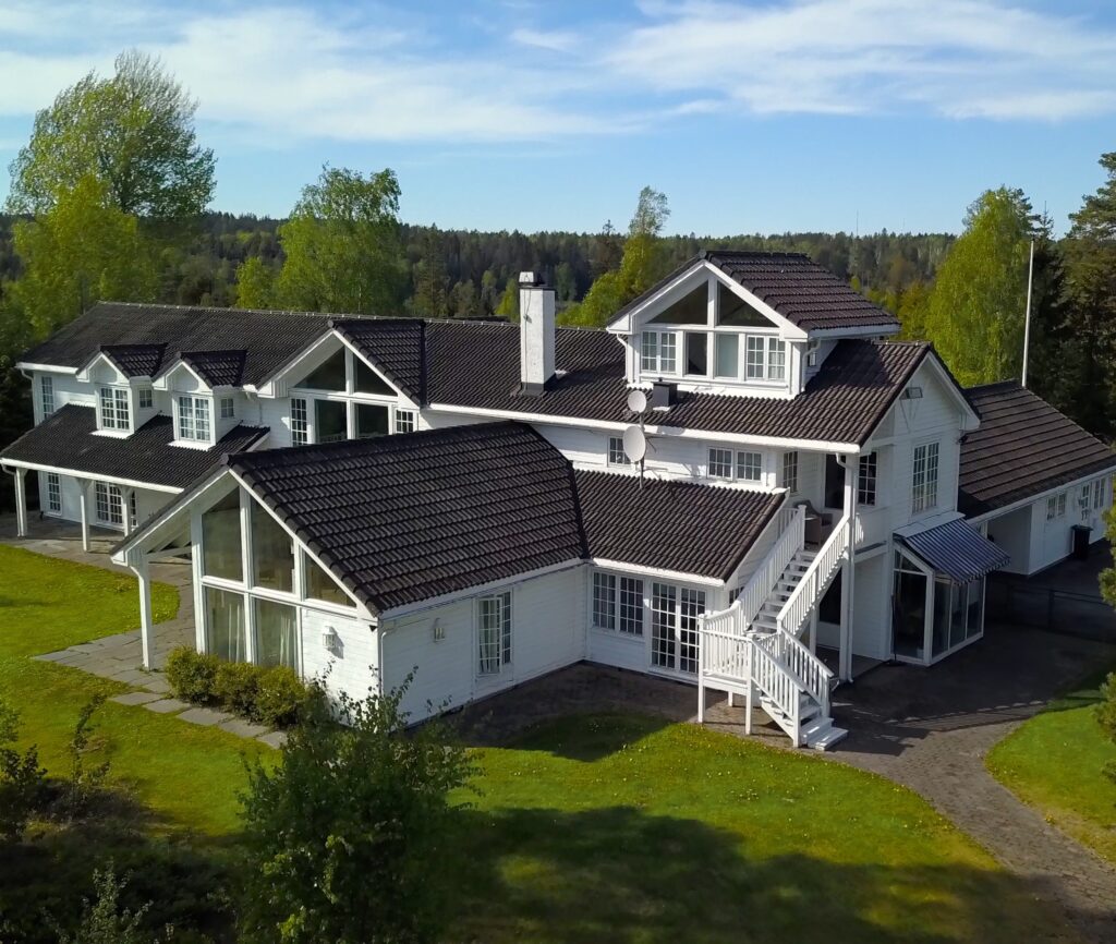 Dronefoto av baksiden av Vendepunktet. Klinikken har naturskjønne omgivelser i Vestby. Hovedbygget er staselig med ranch preg, omkranset av en flott hage og ligger uten innsyn.