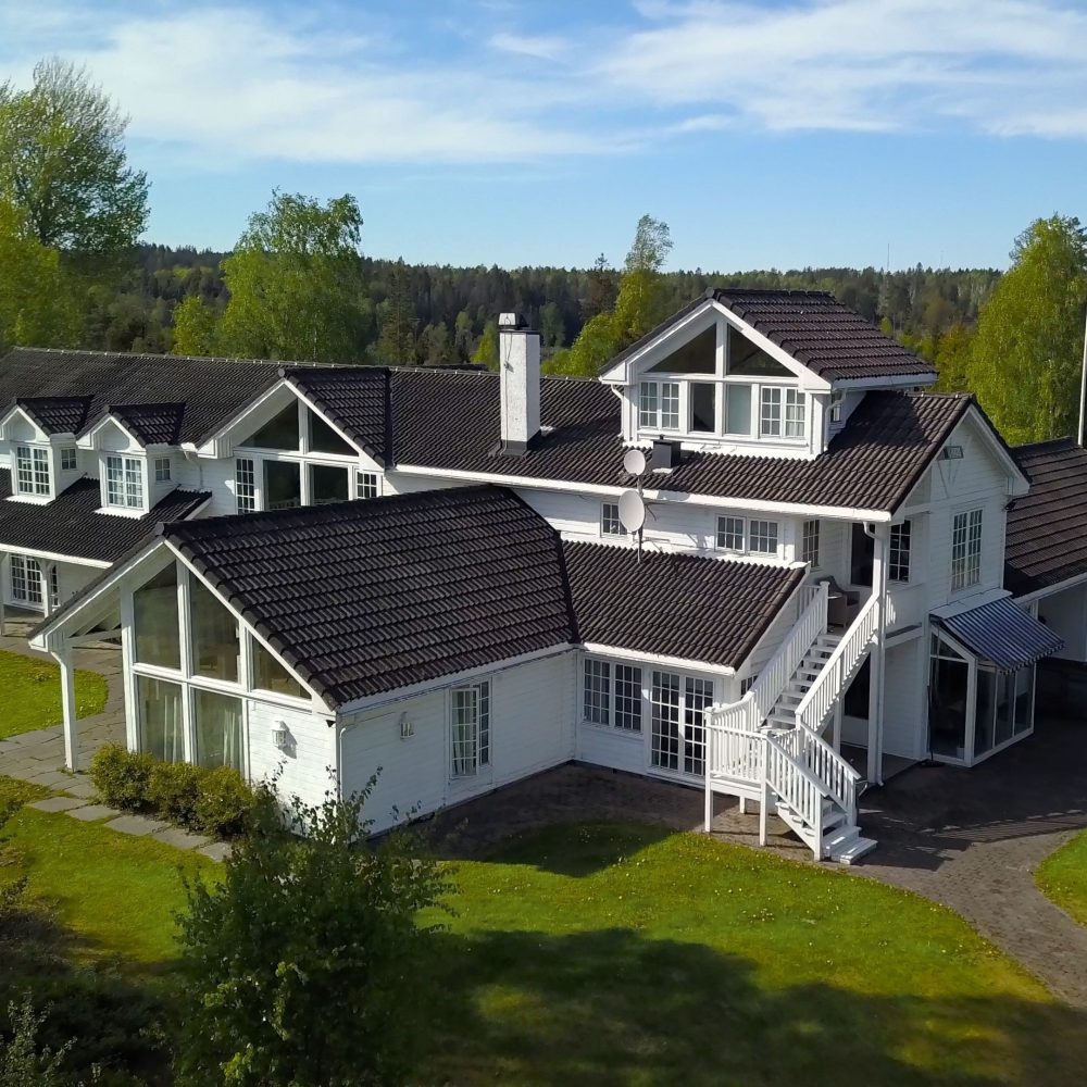 Dronefoto av baksiden av Vendepunktet. Klinikken har naturskjønne omgivelser i Vestby. Hovedbygget er staselig med ranch preg, omkranset av en flott hage og ligger uten innsyn.